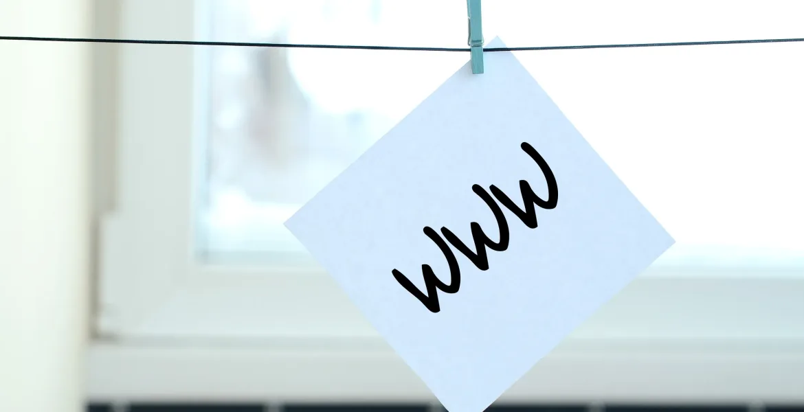 WWW. Note is written on a white sticker that hangs with a clothespin on a rope on a background of window glass